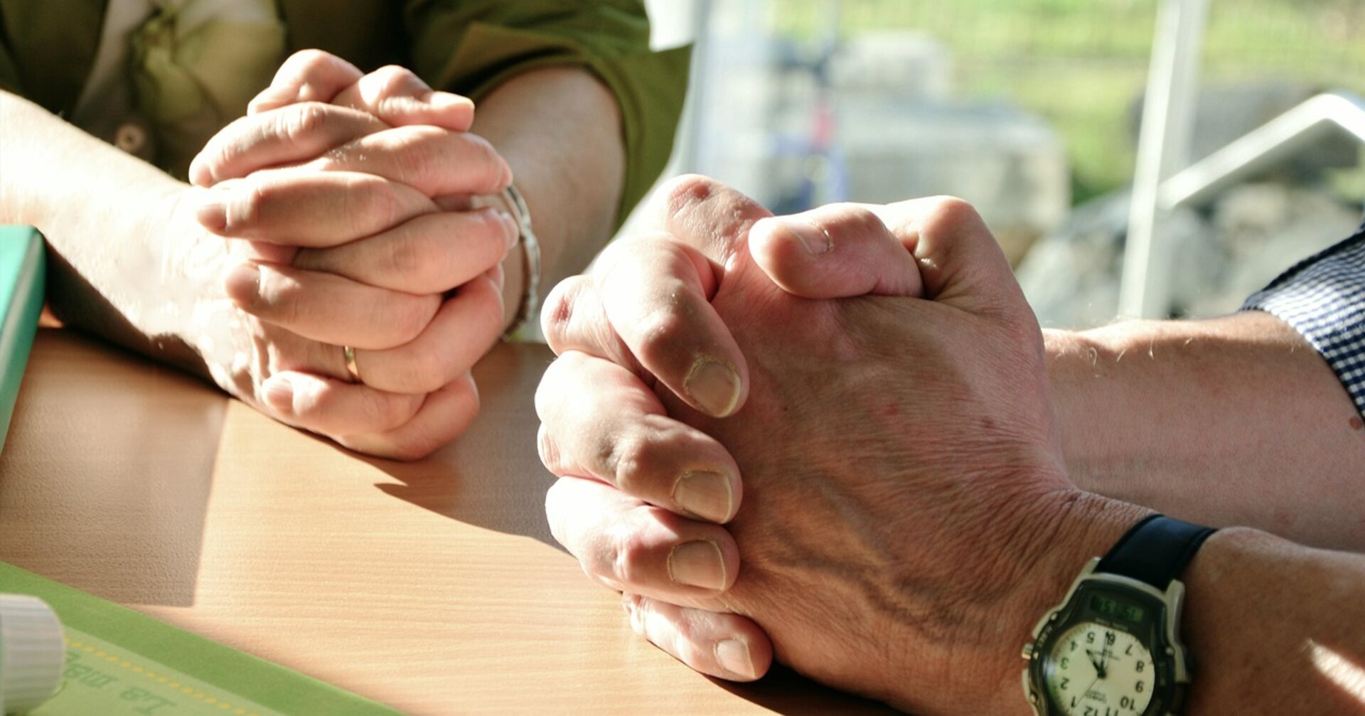 Two people with hands clasped across a table